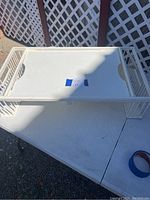 Top view of a white vintage metal table tray showing lattice sides and flat tray surface with hand-holes.