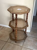Full view of the vintage wooden 3-tier octagonal table showing the overall structure with three woven wicker shelves supported by turned wooden legs.