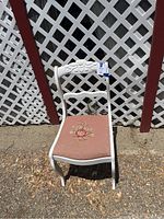 Front view of vintage white wooden chair with carved floral back and floral needlepoint upholstered seat.