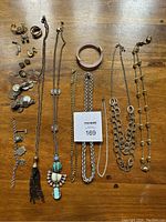 Full lot image showing all necklaces, bracelets, earrings, and brooch on a wood surface.