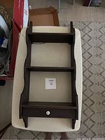 Top-down view of the dark stained wooden wall shelf showing two open shelves and one drawer with a white knob.