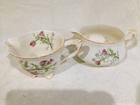 Two vintage Alfred Meakin gravy boats with thistle floral designs, white ceramic with gold trim, photographed side by side