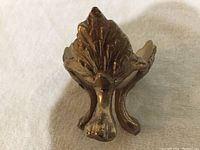 Close-up view of the oak leaf design on one of the brass stand legs showing the detailed leaf pattern and aging patina.