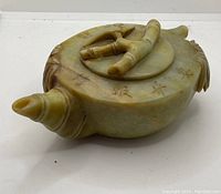 View of the jade teapot with carved bamboo handle and removable lid, showing spout and Chinese character inscriptions on body.