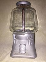 Front view of silver-finished cast metal base with embossed coin door and clear glass globe