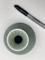 Top view showing circular opening and crackle glaze pattern on celadon green vase with pen for scale.