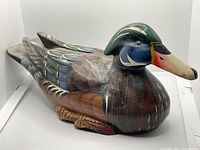 Front and left side view of the hand-carved wooden duck decoy showing detailed carving and paintwork.