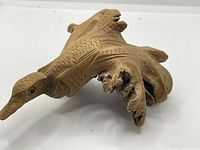 Top and side view showing detailed carving of bird's wings, body, and head with textured feather patterns and pointed beak.