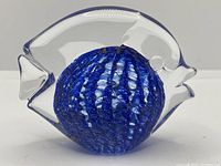 Side view of clear glass fish paperweight showing blue swirl interior.