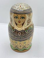 Close up front image showing painted details of the top doll of the nesting set with glitter accents.