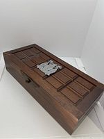 Angled view of the wooden box showing woodwork and emblem on lid