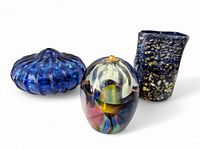 Three vintage blue glass decorative items: a ribbed cobalt glass piece, a short flecked vase, and an iridescent oil wick candle holder.