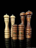 Front view showing three pairs of wooden salt and pepper grinders varying in size and finish.