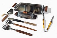Top-down view showing all items in the lot arranged with serving tray, butter dish, wooden salad fork and spoon, spatula, cheese slicer, and Bakelite tongs