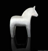 Front and side views of the brushed silver aluminum Dala horse statue, showing minimalist and modernist styling, smooth surfaces with some visible wear.