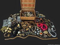 Full spread of vintage jewelry on black surface and in a wicker basket; shows variety of types and styles