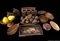 Full lot of wooden and wicker decor and serveware pieces including resin horsehead bookends, wicker utensil basket, various wooden bowls, a wooden tray with elephant inlay, bamboo slat basket with carved wood fruit, and faux lemons on a wooden pedestal bowl shown on a black background.