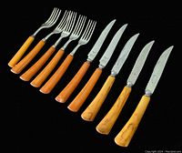 Ten piece set of forks and knives with bakelite handles, arranged on black background