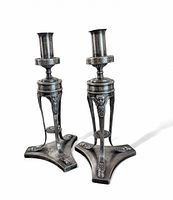 Pair of silver-plated Art Nouveau style candlesticks with cherub motifs and cloven hoof feet shown on white background.