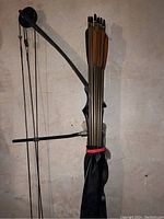 Top view of quiver attached to bow holding arrows; arrows have black fletching and pointed tips, bow is black with a matte finish.