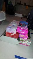 Stack of Barbie doll boxes including Spring Tea Barbie, Disney Fun Barbie, and others on a basement floor.