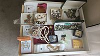 Overall view of boxed vintage jewelry collection containing necklaces, bracelets, pearl strands, earrings and compact case.