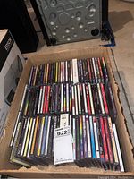 Box of assorted CDs in jewel cases, arranged in rows in a cardboard box