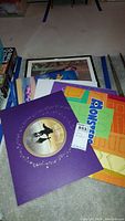 Stack of Disney lithographs and folders including purple Beauty and the Beast folder and Monsters Inc folder