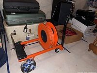 Side view of hand truck with attached orange extension cord reel and orange extension cord.