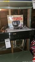 Photo showing Pioneer LD-870 LaserDisc player, Coby 5-inch black & white TV on top of it and original box in background.