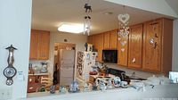 Photo of kitchen wall showing hanging barometer and various wind chimes on display above kitchen counter