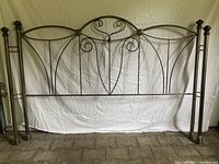 Front view of the brass metal king size headboard showing full design, scrollwork, and posts.