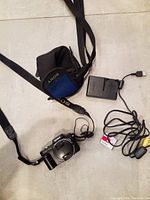 Sony Cyber-shot camera with strap, charger, cables, and case all laid out on floor.