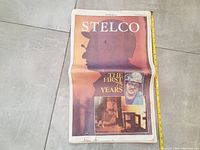 Front view of the Stelco The First 75 Years commemorative newspaper with a worker silhouette and some damage visible on the front page.