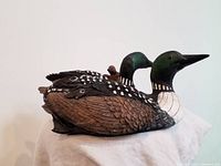 Photo showing the two loon figurines side by side on a white cloth for scale and detail visibility.