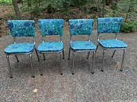 Front view of all four vintage chairs showing blue floral vinyl seat and back upholstery with chrome frames.