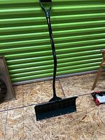 Front view of the snow shovel showing the poly blade and ergonomic curved handle with D-grip