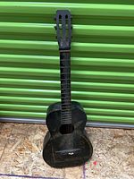 Full front view of the antique Hawaiian guitar with hand-painted gold artwork on a black body.