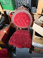 Front view of antique Victorian wooden chair featuring red velvet tufted upholstery on round backrest and seat, with carved wooden details on frame.