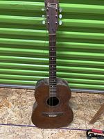 Full front view of the Granada acoustic guitar showing worn wooden finish, neck with tuning pegs, and missing bridge area.