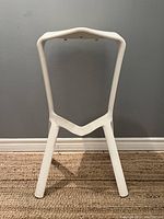 Front view of the white Miura stool plank showing its distinctive geometric open frame and three legs.