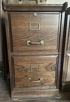 Front view of a 2-drawer wooden filing cabinet showing metal handles, label holders, and key lock on the top drawer