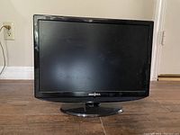 Front view of black Insignia 19 inch TV on stand against a beige wall.