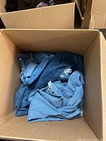 Open box with a mix of blue denim jeans, some with distressed/ripped design, various adult sizes