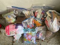 Photo showing bags of craft materials including yarn, stuffing, glue sticks, orange and white pipe cleaners, popsicle sticks, foam, and other items.