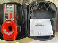 Black and Decker red and black laser level tool inside an open black hard carrying case with instruction manual.