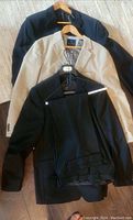 Three mens designer sports jackets laid flat; black, beige, and dark navy colors visible. All size 44, gently worn condition.