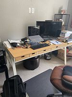 Full view of IKEA desk with computer monitor, wired keyboard, laptop, and various papers on top.