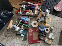 Overview of painting and wall repair tools including rollers, brushes, tape, sandpaper, mask, and spackling paste.