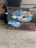 Intex Splash'N Chill Island float in box with image of six people sitting and relaxing on the blue and white inflatable float on water.
